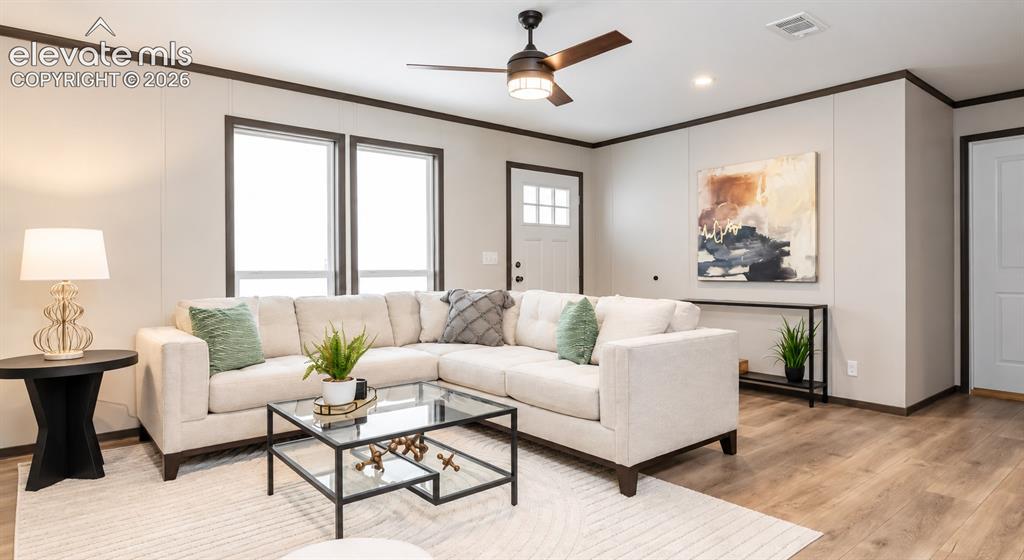 Image 3 of 6: Living area featuring wood-finish flooring, neutral wall tones, high-contra