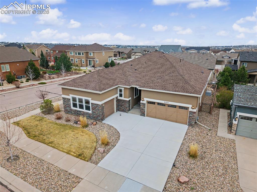 Caption: View of front of home with an attached garage, stone siding, stucco siding, and concrete driveway