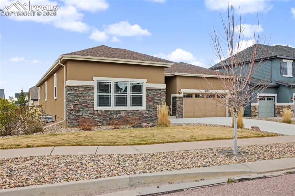Image 10 of 40: Prairie-style house with stucco siding, a garage, driveway, and stone sidin