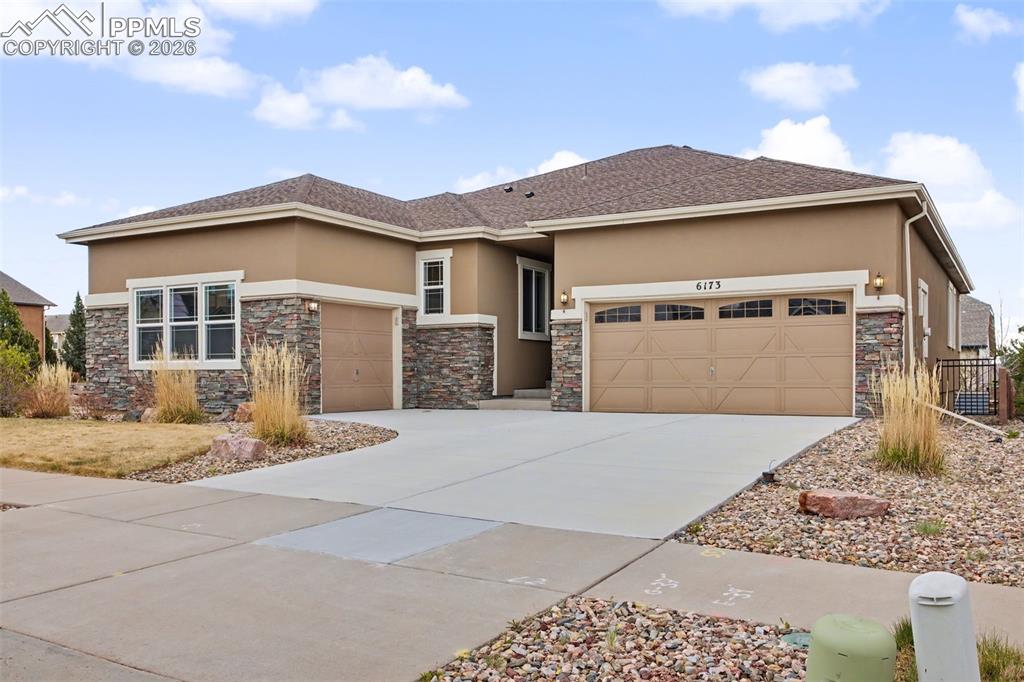 Image 11 of 40: Prairie-style house featuring stone siding, an attached garage, stucco sidi