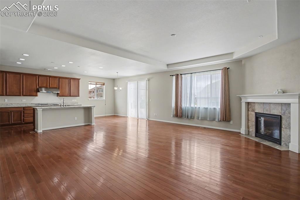 Image 12 of 40: Unfurnished living room featuring a tiled fireplace, dark wood finished flo
