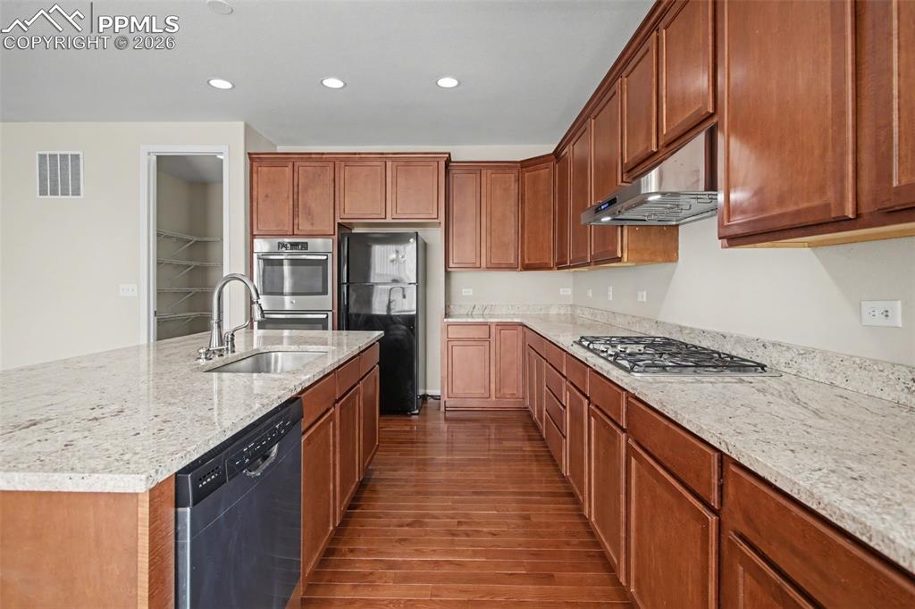 Image 15 of 40: Kitchen with black appliances, a center island with sink, recessed lighting