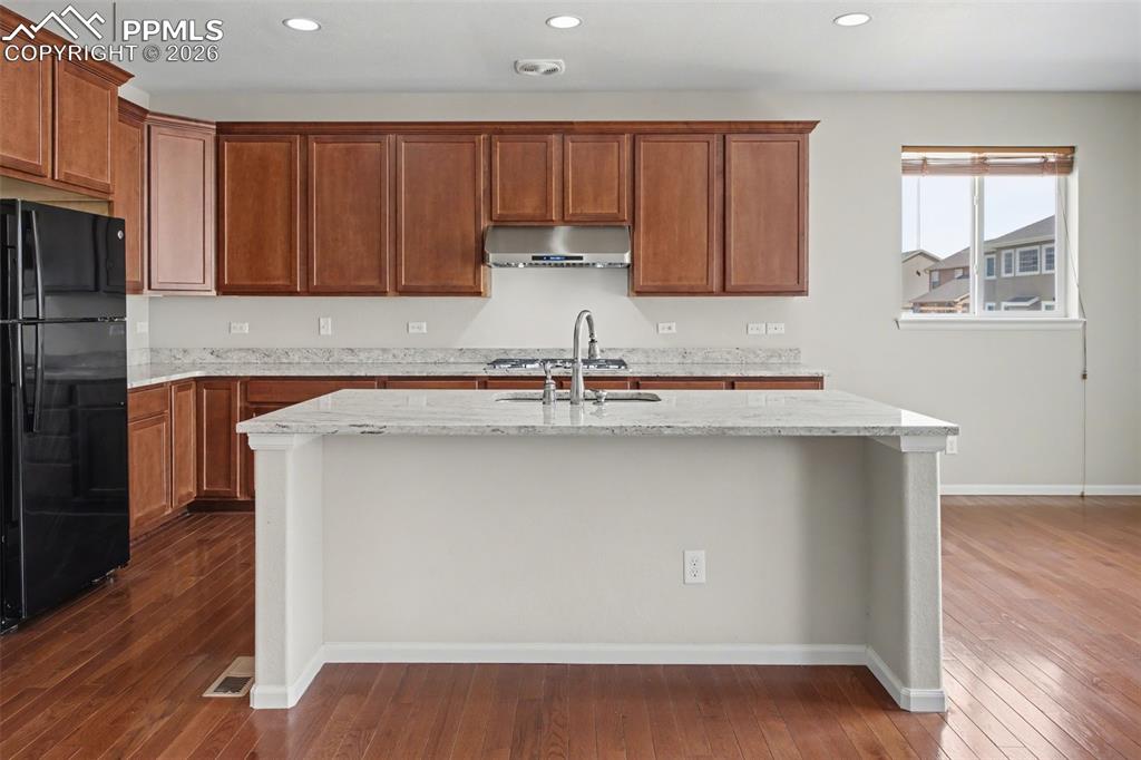 Image 16 of 40: Kitchen featuring freestanding refrigerator, a center island with sink, lig