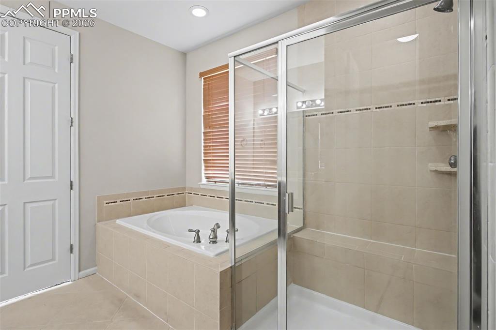 Image 22 of 40: Bathroom featuring a stall shower, light tile patterned floors, a garden tu