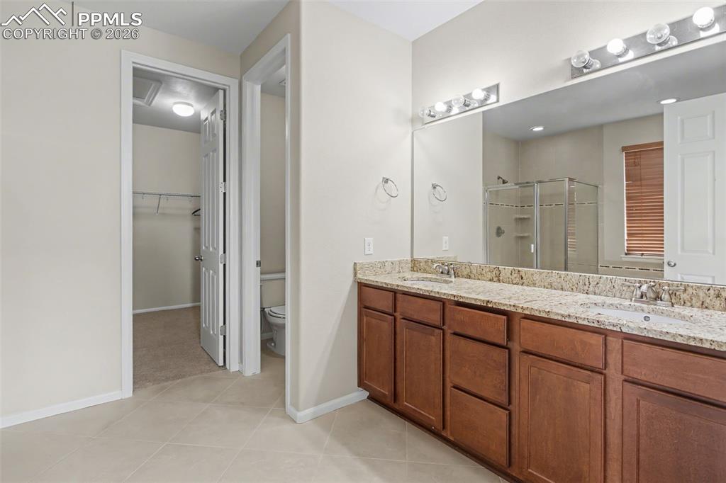 Image 23 of 40: Full bathroom featuring double vanity, a stall shower, a walk in closet, an
