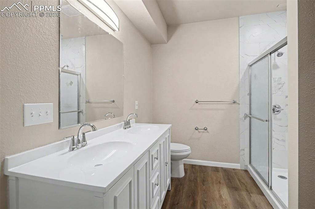 Image 26 of 40: Bathroom with a textured wall, a marble finish shower, double vanity, and d