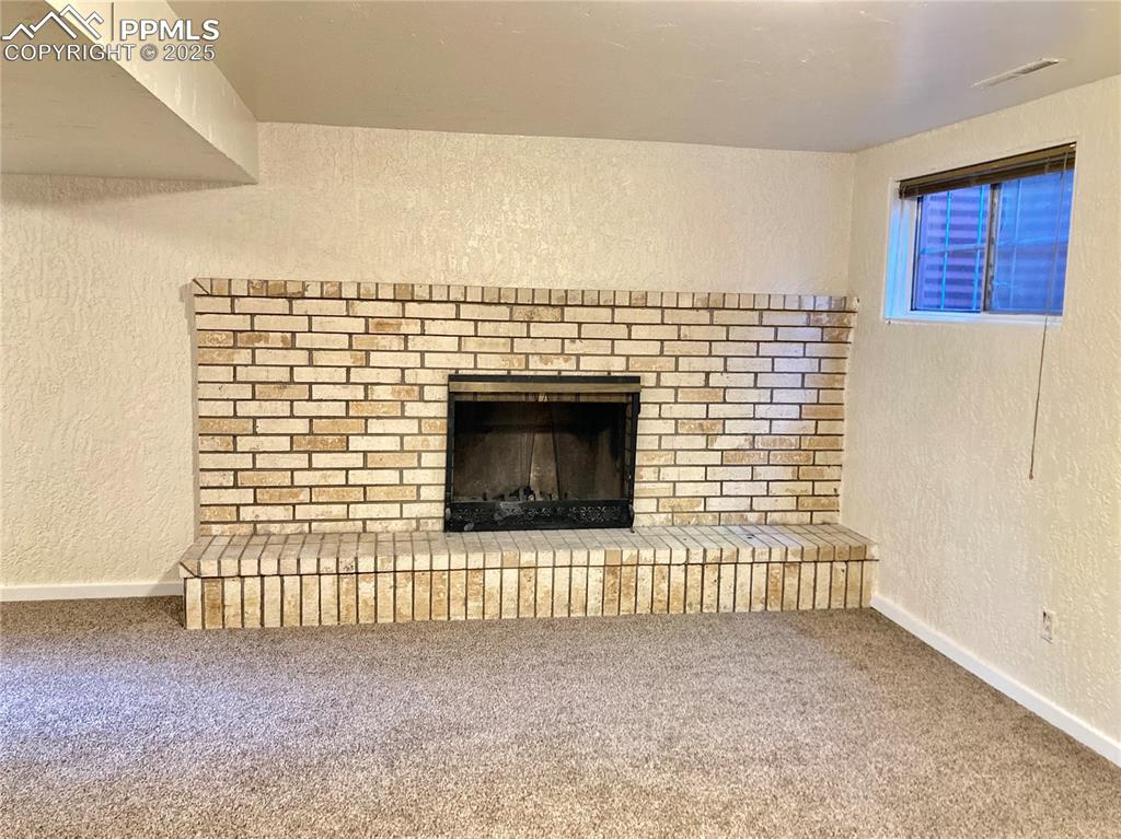 Image 28 of 43: Basement family room includes a wood-burning fireplace.