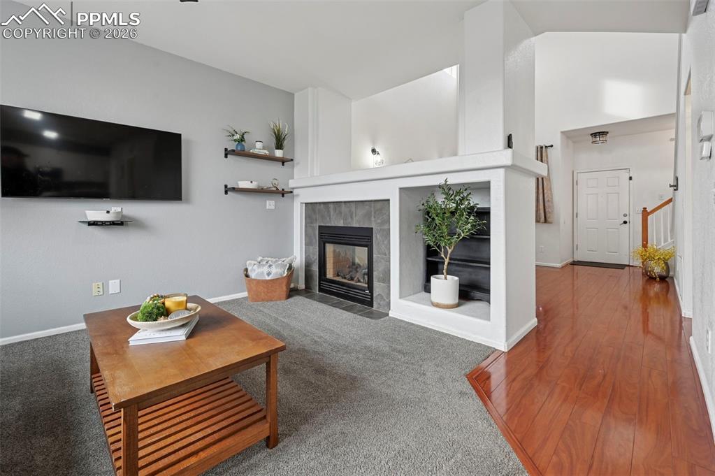 Image 6 of 49: Family room, large picture window, double-sided fireplace, carpet, adjoins 