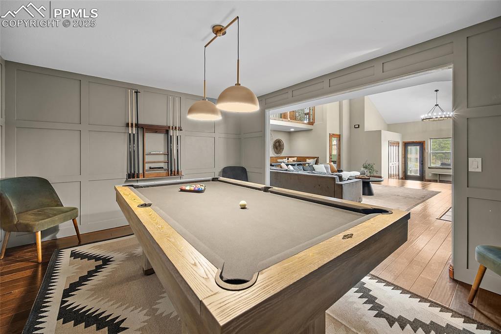 Image 13 of 47: Playroom with a decorative wall, billiards, wood-type flooring, a chandelie