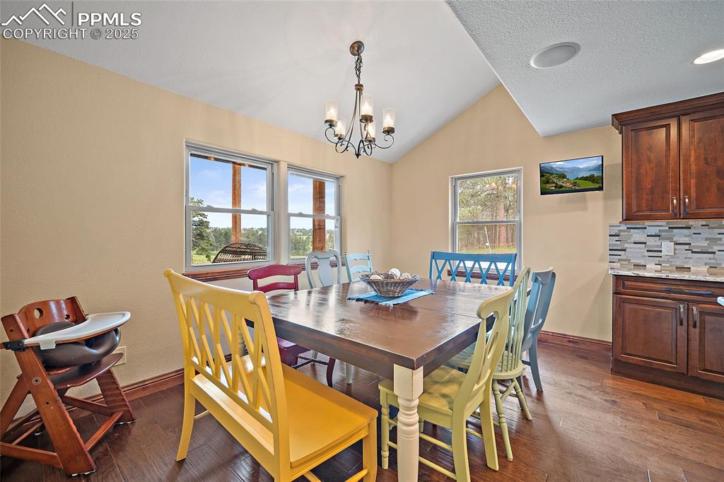 Image 16 of 47: Dining area with lofted ceiling, a chandelier, dark wood-style floors, and