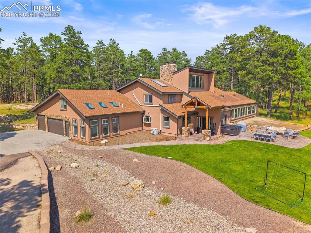Image 2 of 47: Rear view of house with driveway, a lawn, a patio, and a chimney
