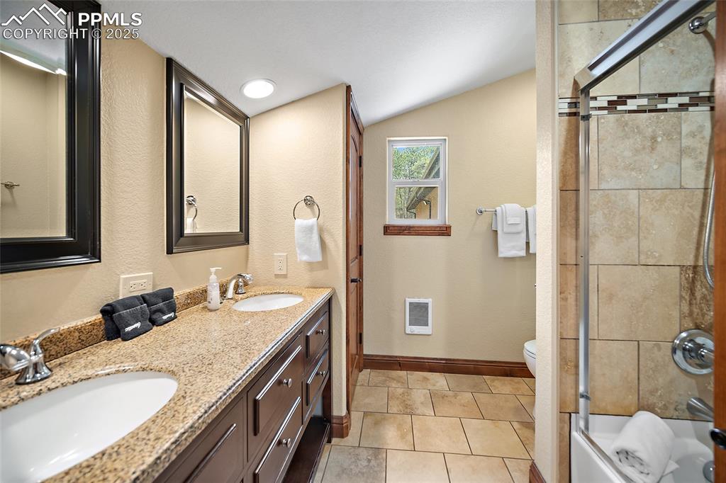 Image 36 of 47: Bathroom featuring lofted ceiling, double vanity, shower / bath combination