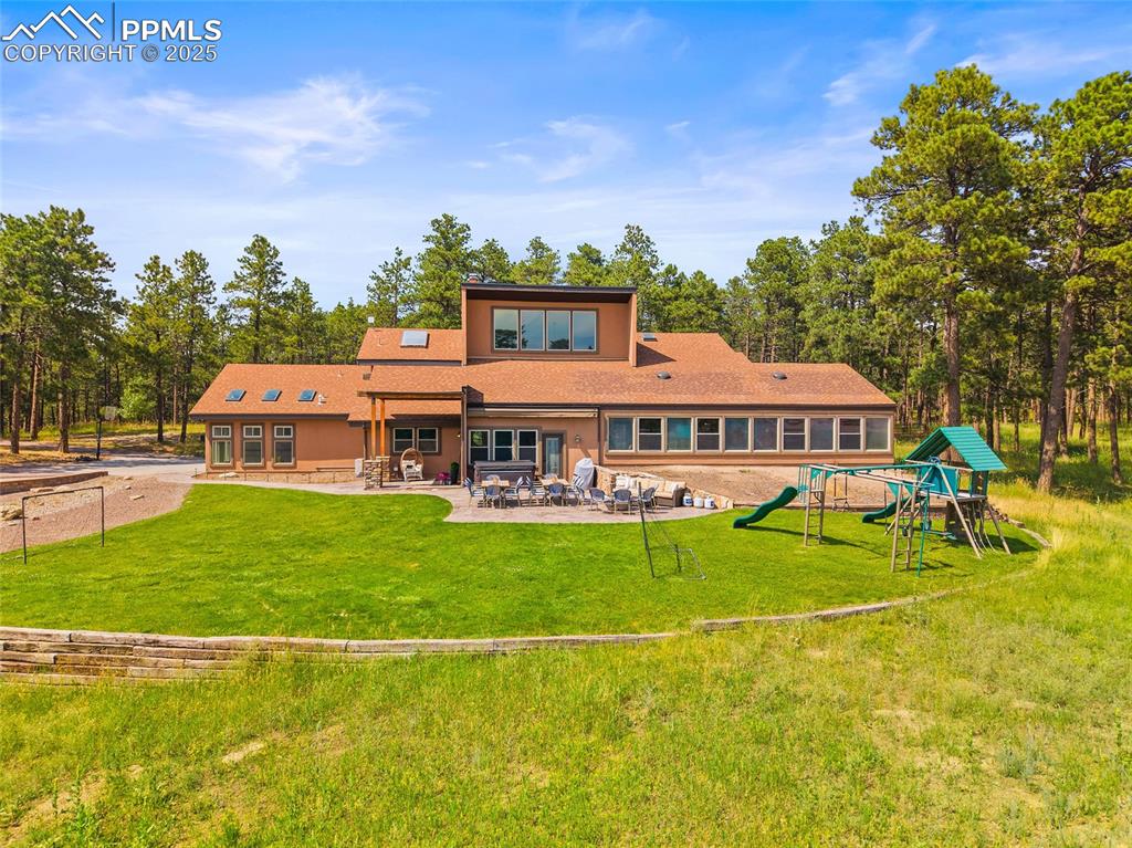 Image 44 of 47: Rear view of house featuring a patio area, a lawn, and roof with shingles