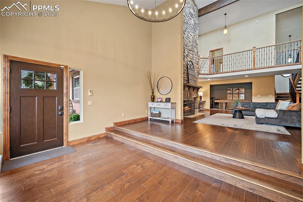 Image 5 of 47: Foyer entrance featuring wood-type flooring, stairway, a stone fireplace, b