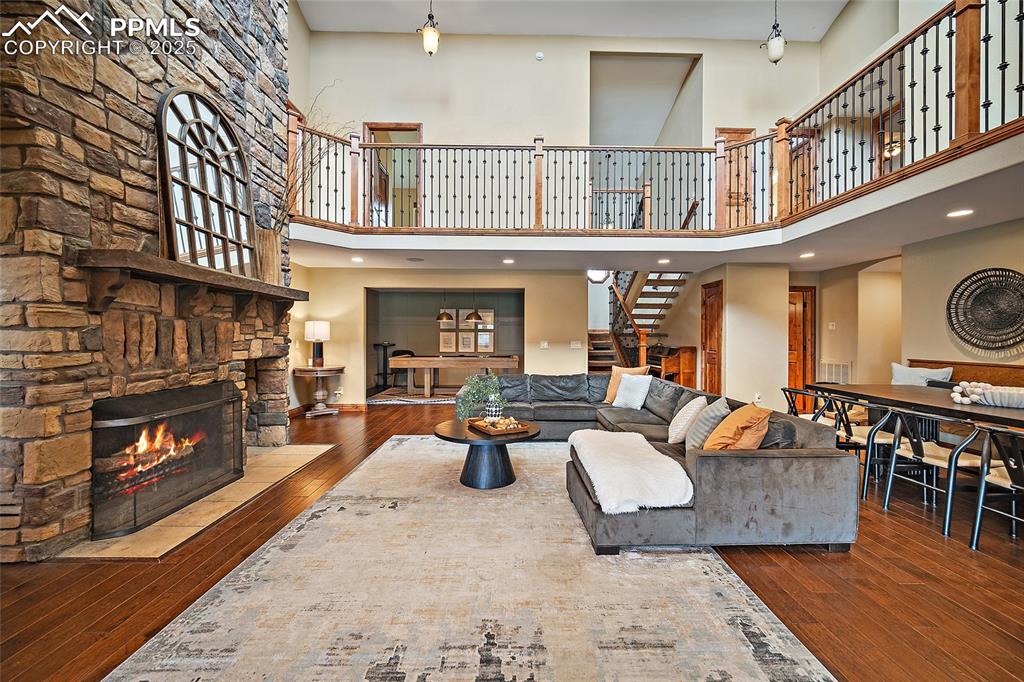 Image 7 of 47: Living area with wood-type flooring, a stone fireplace, stairs, recessed li