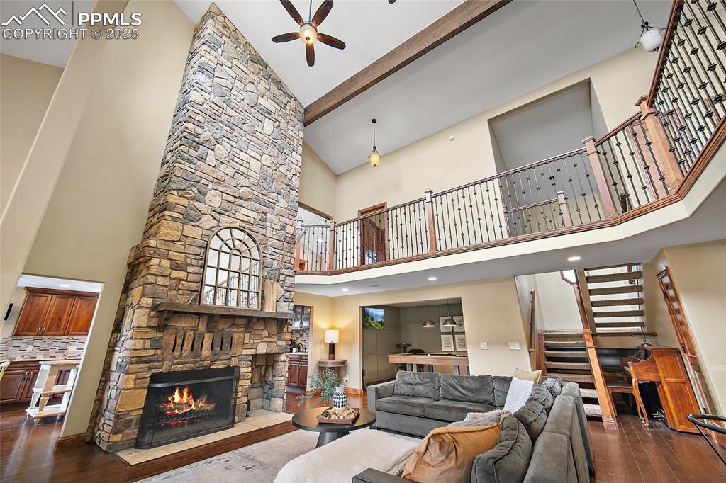 Image 8 of 47: Living area featuring wood finished floors, a ceiling fan, stairway, beam c