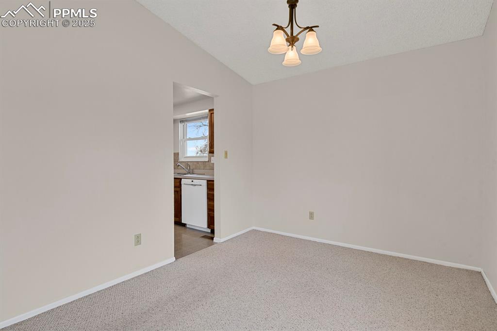 Image 12 of 45: Empty room featuring light carpet, a chandelier, and lofted ceiling
