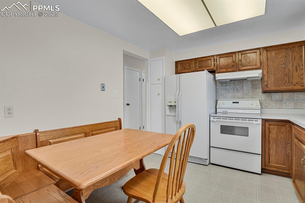 Image 14 of 45: Kitchen featuring white appliances, brown cabinetry, light countertops, dec