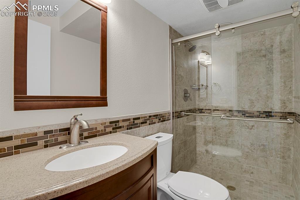 Image 33 of 45: Full bath with vanity, a shower stall, and a textured wall