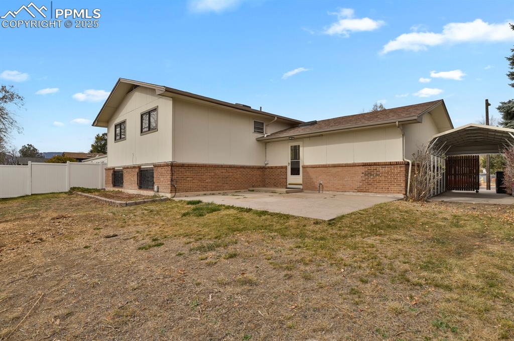 Image 39 of 45: View of side of home featuring a patio area, brick siding, and a detached c