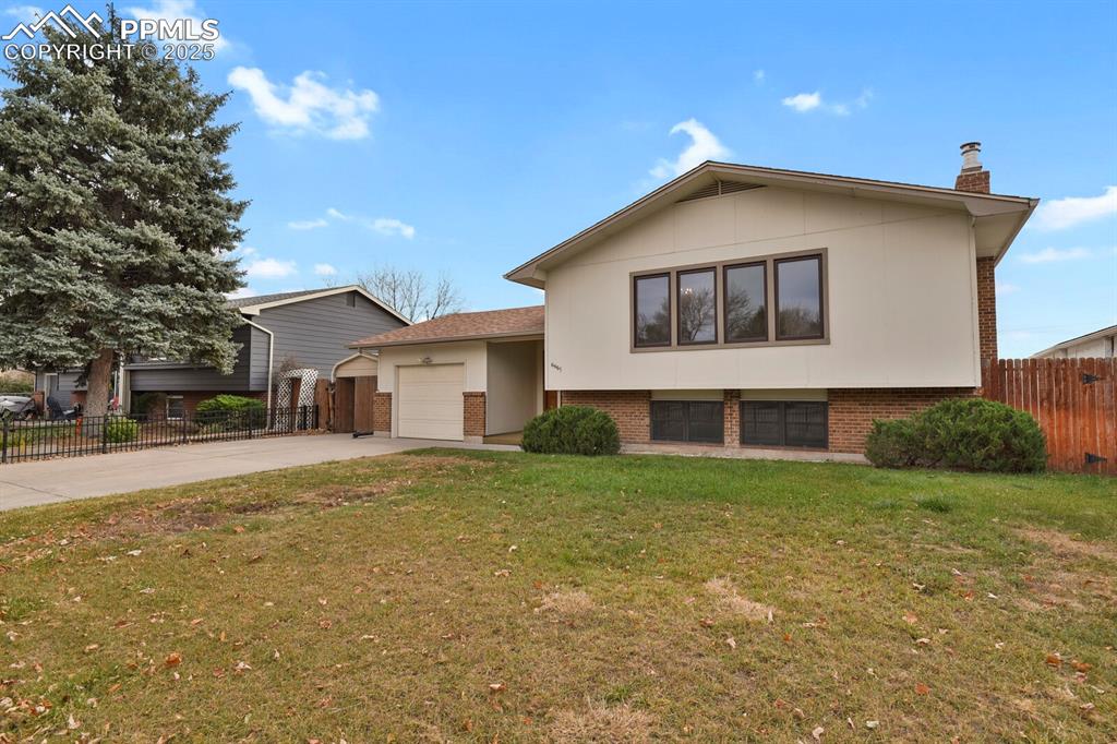 Image 4 of 45: Tri-level home featuring brick siding, driveway, a chimney, and an attached
