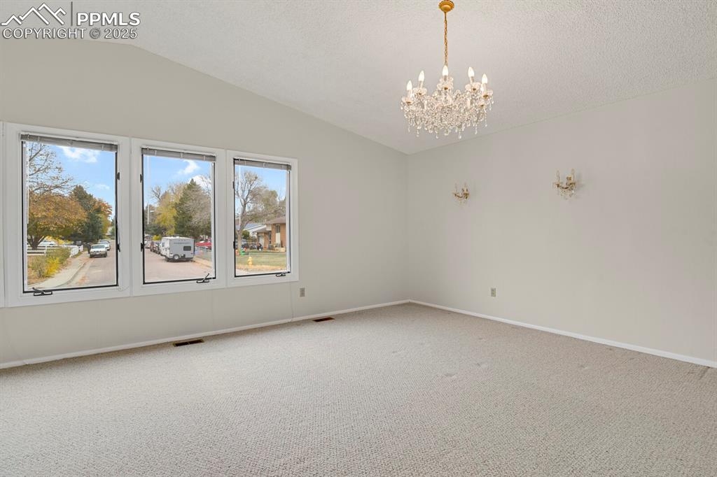 Image 8 of 45: Carpeted spare room featuring lofted ceiling and a chandelier