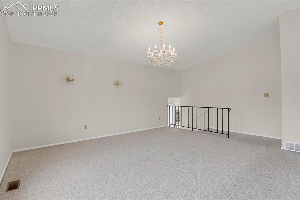 Image 9 of 45: Spare room with carpet flooring, a chandelier, and a textured ceiling