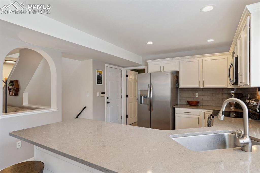 Image 10 of 40: Updated kitchen with stainless steel appliances, white cabinets, a peninsul
