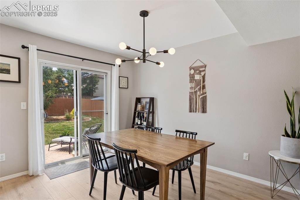 Image 12 of 40: Dining room featuring a chandelier and light LVP flooring with a sliding gl