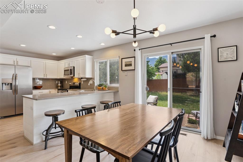 Image 13 of 40: Dining room featuring a chandelier and light LVP flooring with a sliding gl