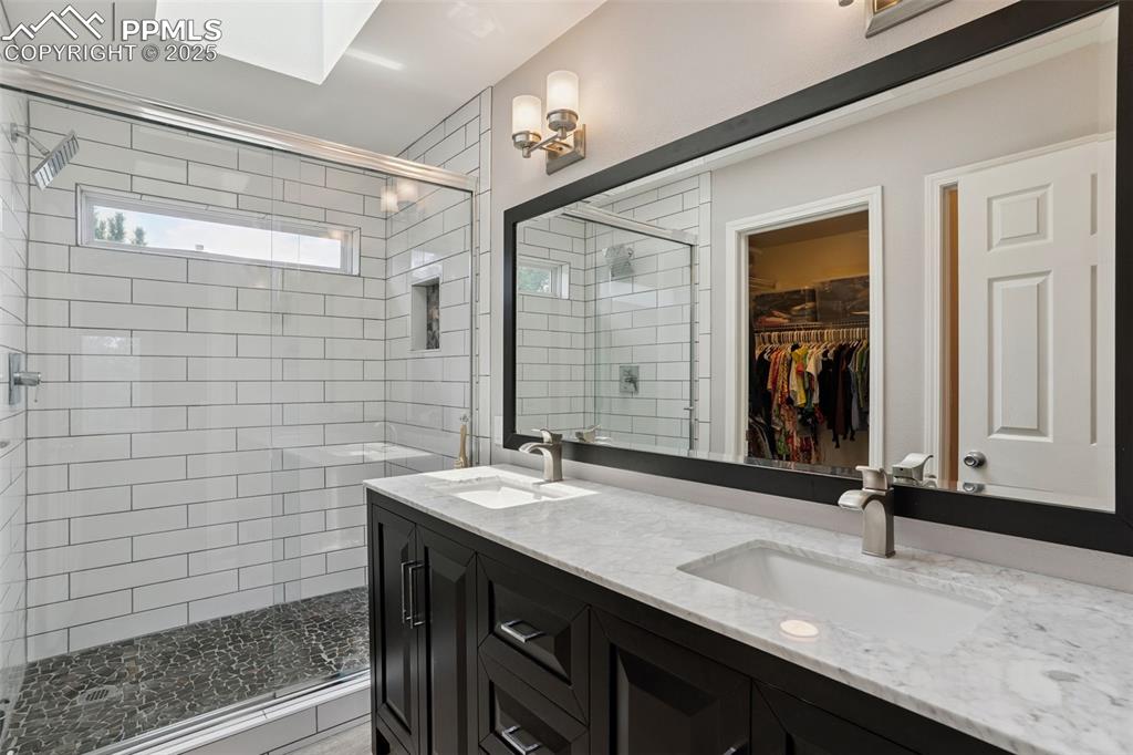 Image 20 of 40: Primary bath featuring a walk in closet, double vanity, a luxurious shower,