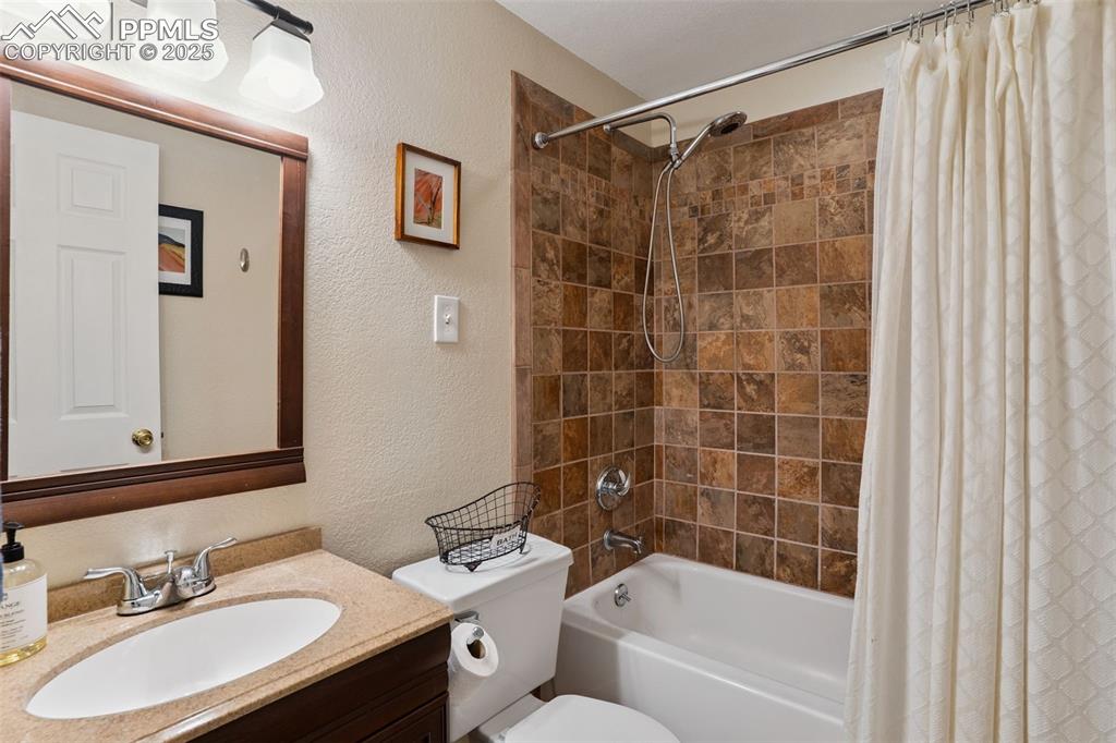 Image 31 of 40: Basement bathroom with a textured wall, vanity, and shower / bathtub combin