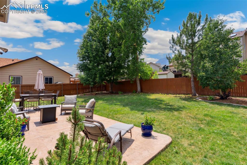 Image 32 of 40: Fenced backyard featuring mountain views, a patio and outdoor dining area