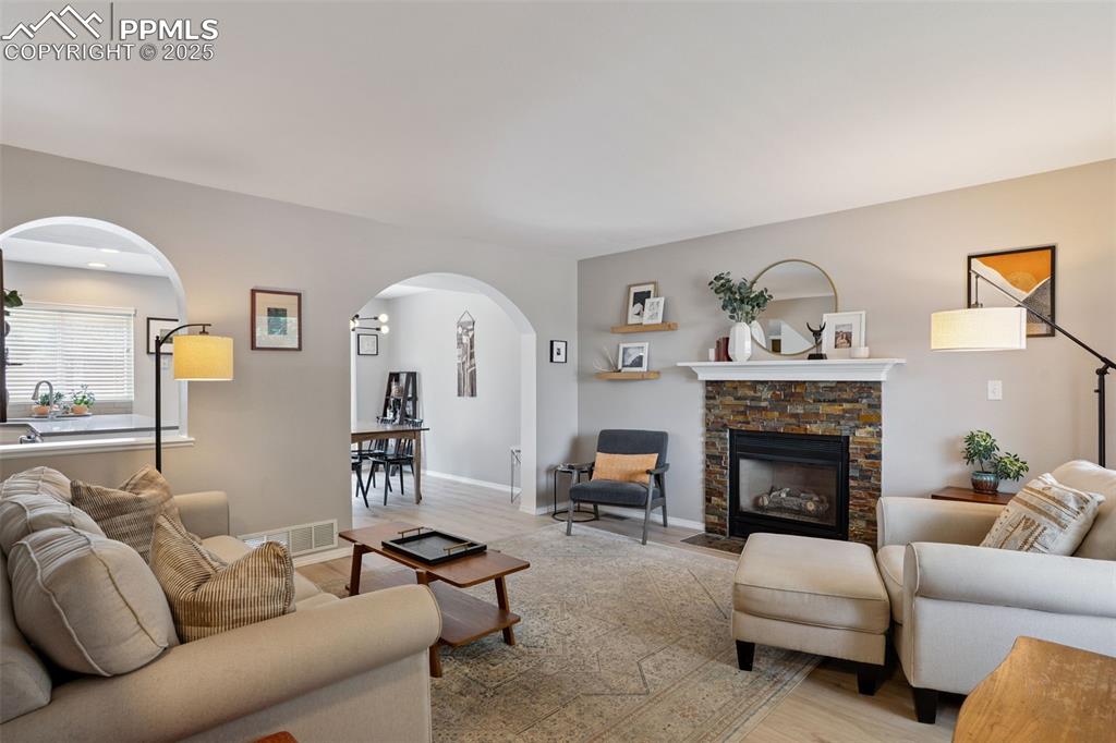 Image 5 of 40: Living area featuring arched walkways, light LVP, and a fireplace