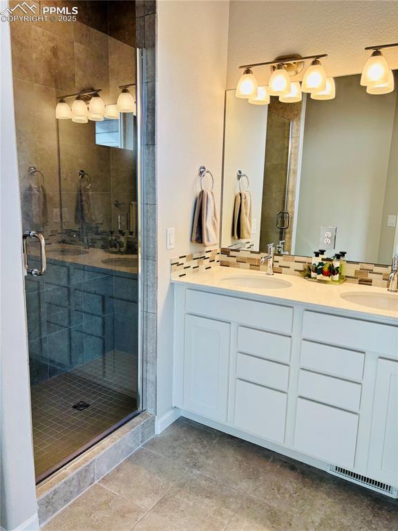 Image 9 of 11: Bathroom featuring double vanity, a shower stall, and light tile patterned 