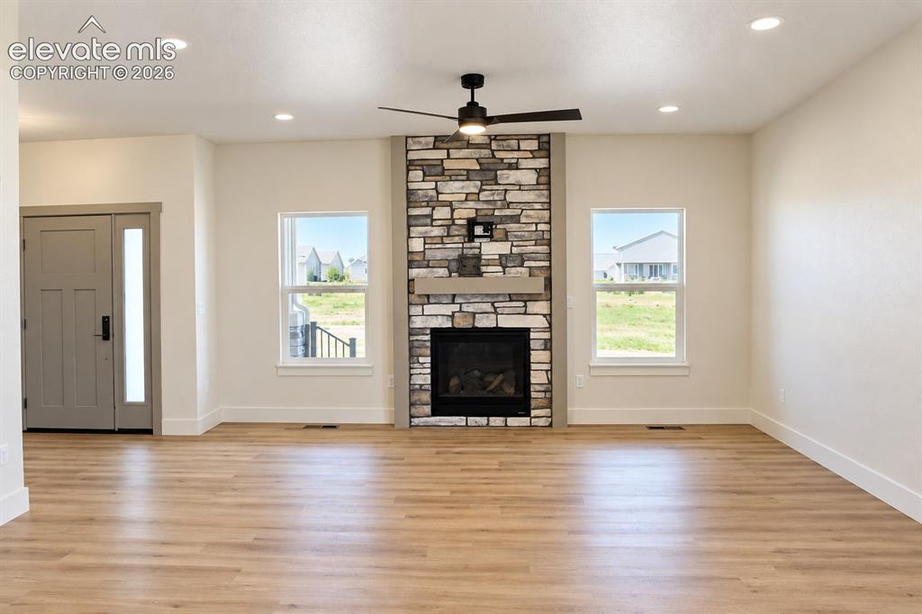 Image 12 of 44: Living area featuring a stone-clad fireplace, wood-finish flooring, recesse