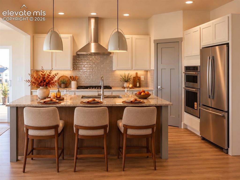 Image 13 of 44: Gourmet kitchen featuring a center island with sink, wood-finish flooring,