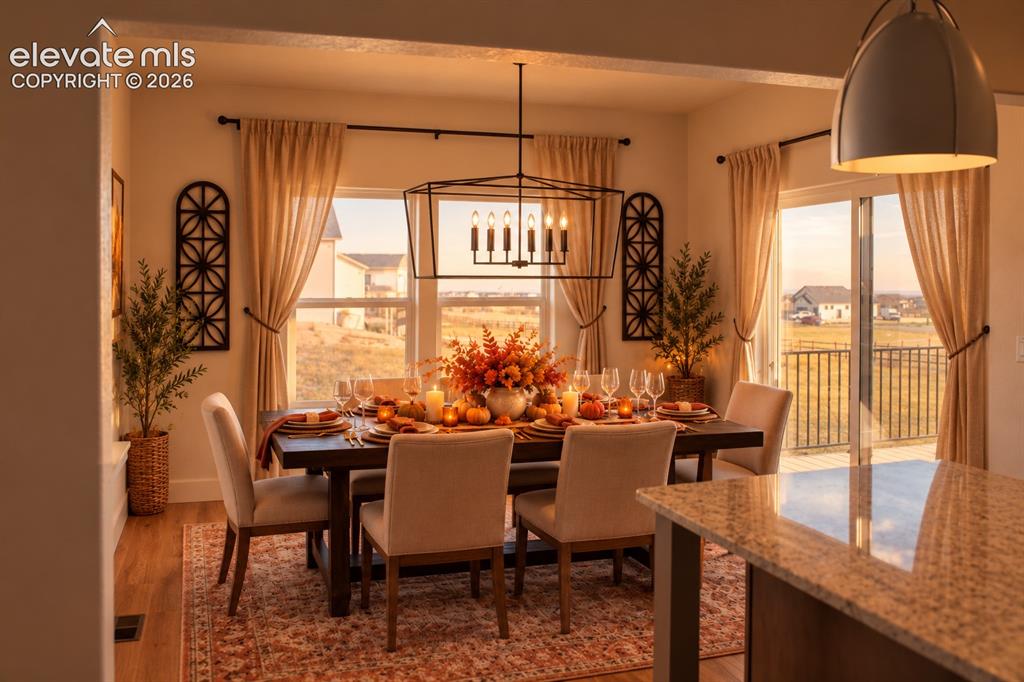 Image 15 of 44: Dining area featuring wood-finish flooring, a contemporary linear chandelie