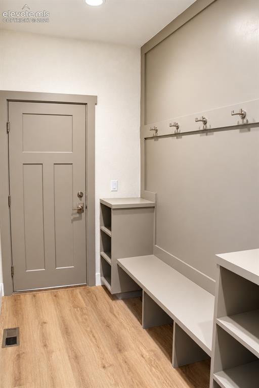 Image 20 of 44: Wood-finish flooring, recessed lighting, and built-in storage bench with sh
