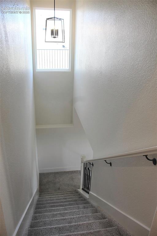Image 24 of 44: High ceilings, carpeted stairs, and a rectangular window with a black iron