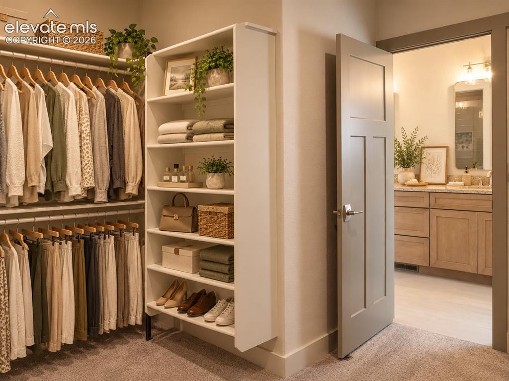Image 28 of 44: Expansive walk-in closet with carpet flooring, built-in shelving, and hangi