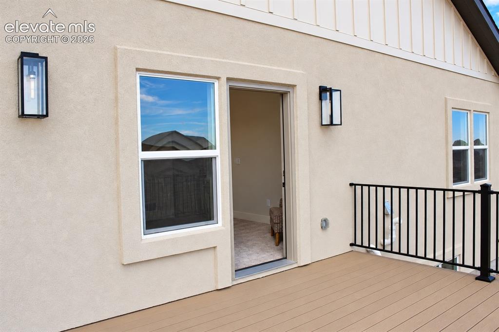 Image 33 of 44: Exterior deck with composite decking, black metal railing, and stucco sidin
