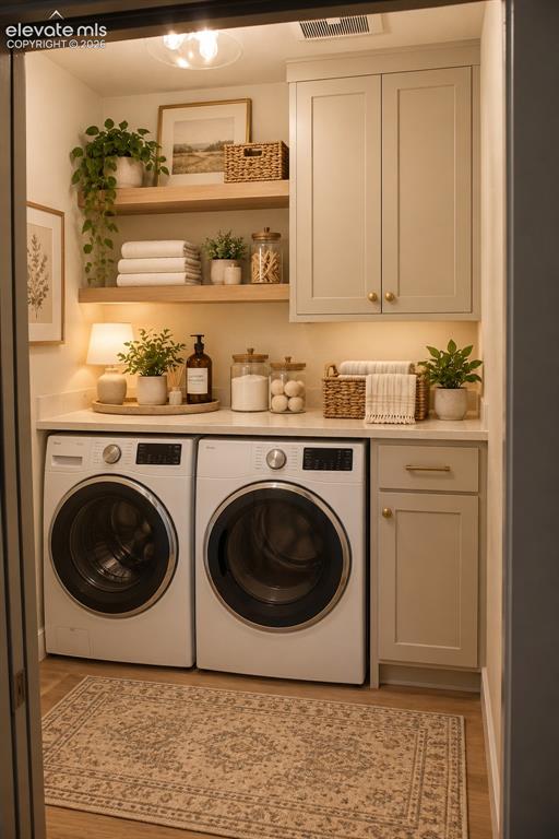 Image 36 of 44: Laundry area featuring a side-by-side washer and dryer, shaker-style cabine