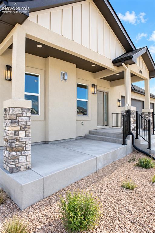 Image 4 of 44: Stucco exterior featuring board and batten gables, stone-clad columns, a co