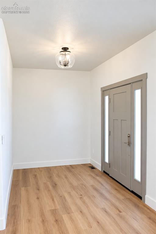 Image 8 of 44: Wood-finish flooring, white walls, modern ceiling light fixture, grey door 