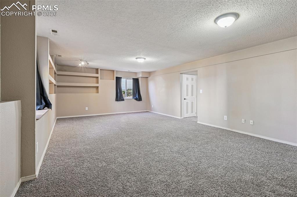 Image 22 of 35: Basement Family room - garden level with built-in shelves and new carpet