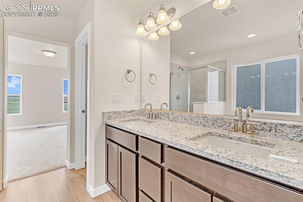 Image 25 of 29: Full bathroom with wood finished floors, double vanity, a shower stall, and