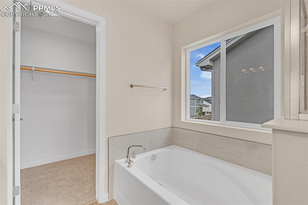 Image 26 of 29: Full bathroom with a bath and a walk in closet