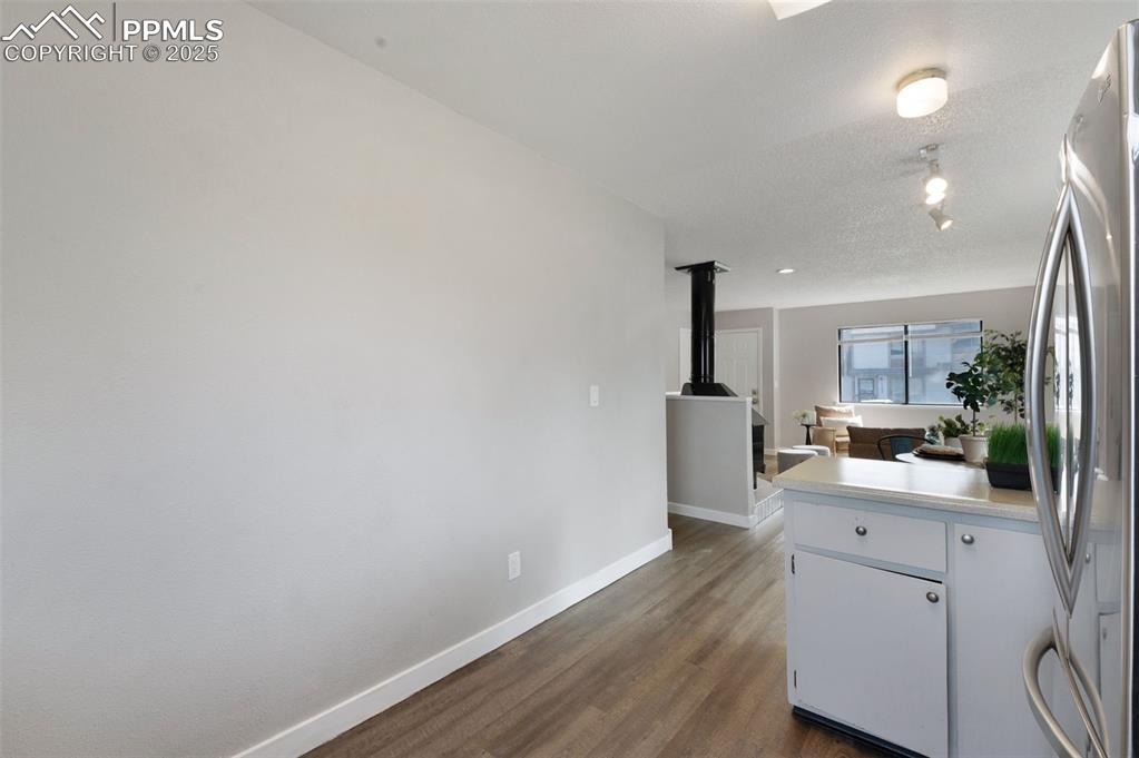Image 10 of 26: Kitchen with freestanding refrigerator, dark wood-type flooring, light coun