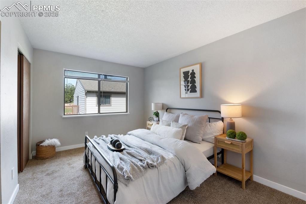 Image 12 of 26: Carpeted bedroom featuring a textured ceiling and baseboards